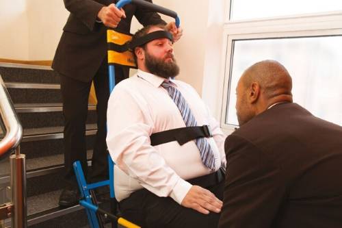 two men assist wheelchair stairs